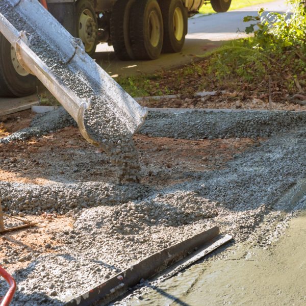 Mixer truck pouring wet cement ready mixed concrete for driveway near home